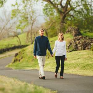 Middle aged couple walking through woods on road holding hands