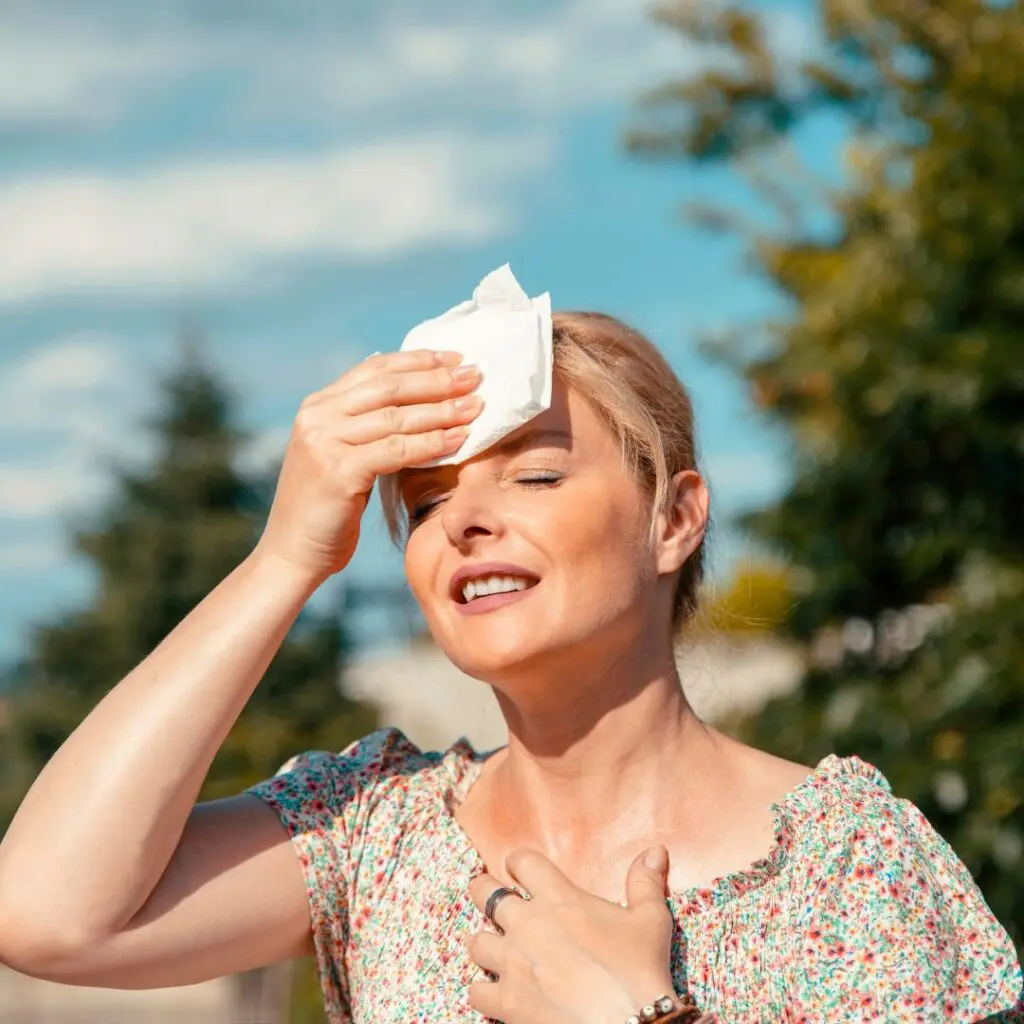 woman in sunlight holding head while experiencing flashes and floaters in eyes
