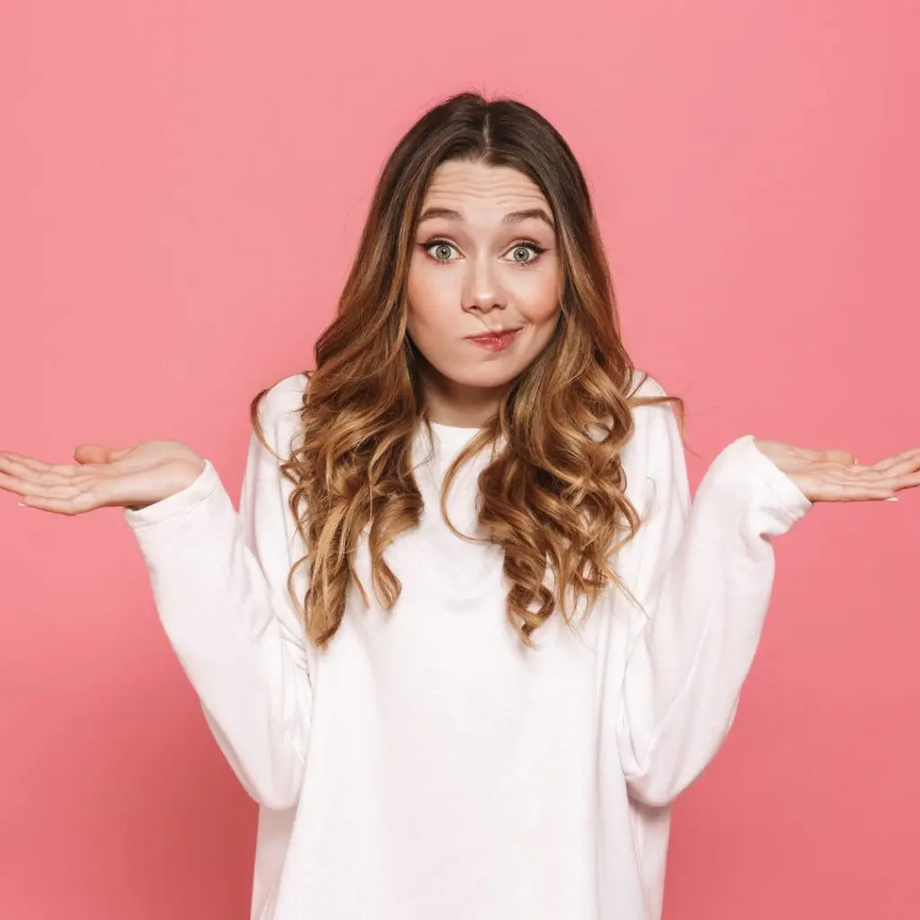 Centre for Sight Young Lady Shrugging pink background pursed lips to the side confused