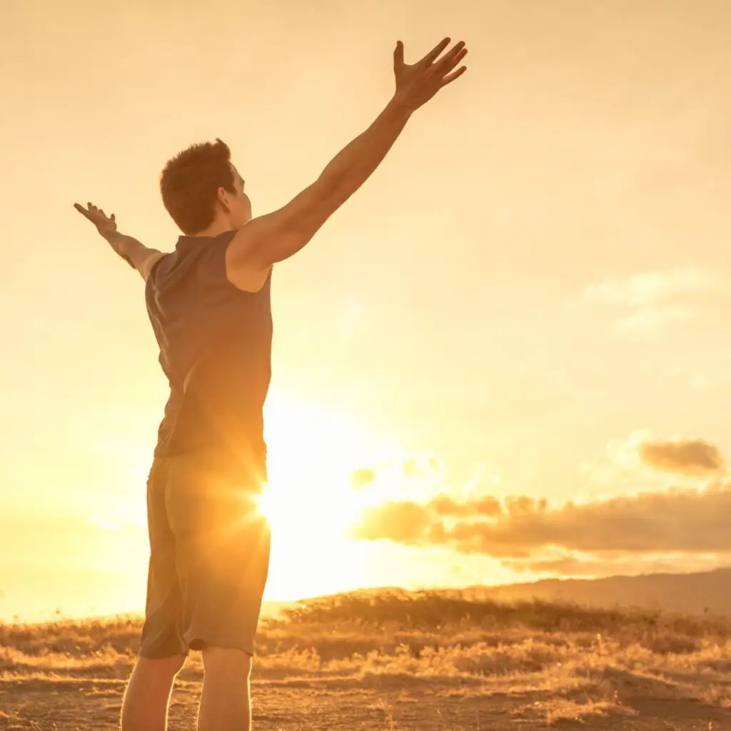 Centre for Sight Man feeling rejuvenated after laser eye surgery looking at sunset with arms out experiencing freedom shorts and tanktop