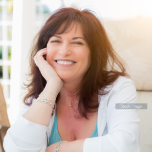 Lady smiling with hand on face with white cardigan