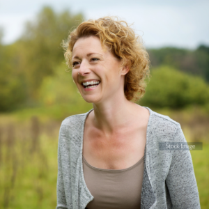 Lady smiling outside with grey cardigan curly short blonde hair