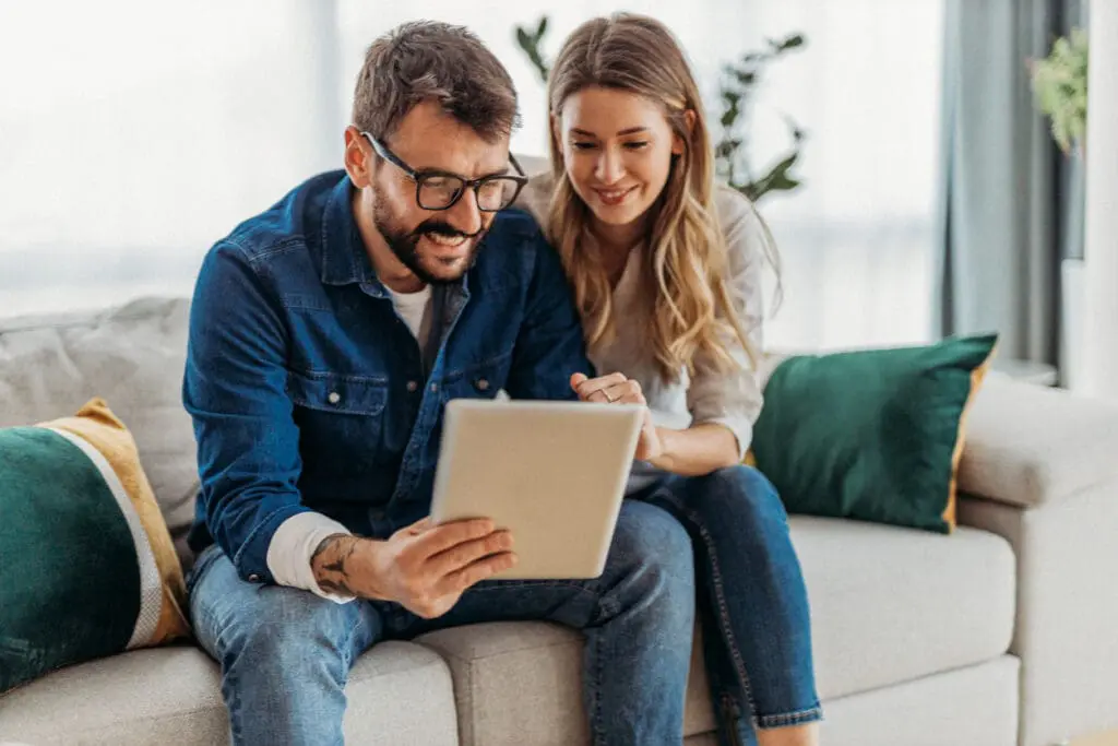 Centre for Sight - a couple sat on sofa reading a tablet, the male is wearing glasses the female not.