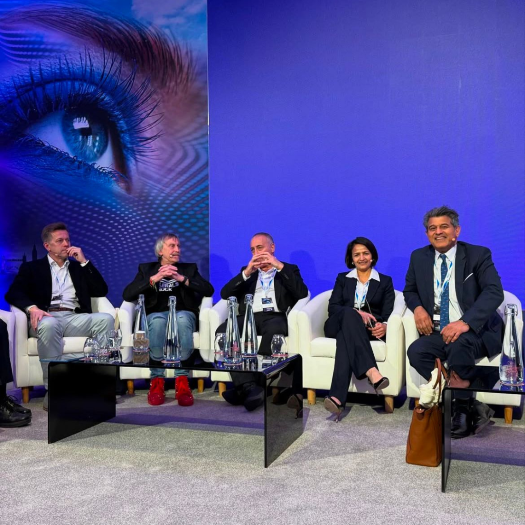 Colleagues on stage and Sheraz Daya eye surgeon sitting down grouped having photograph taken at event of 75 years of the Intraocular Lens Implant