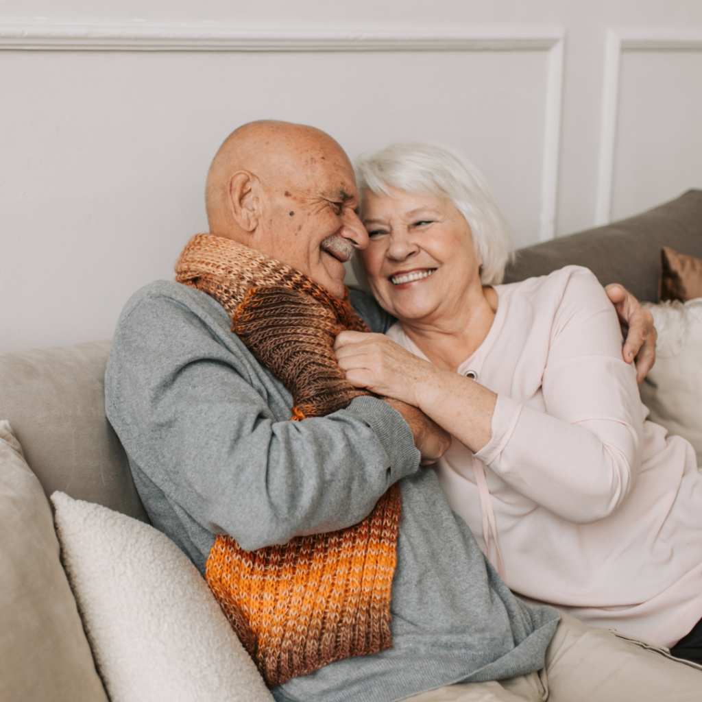 Older Man and Lady Cuddling on Sofa Smiling Following Cataract Surgery Stock Image