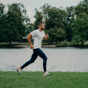 Young Man running on grass along riverbank