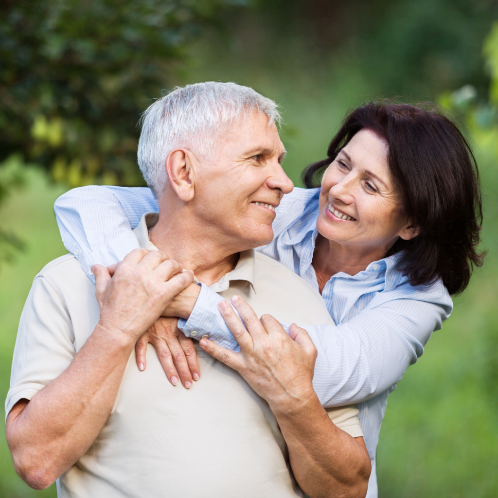 Couple in garden hugging grey haired man and brunette woman looking at each other smiling after 2RT laser treatment