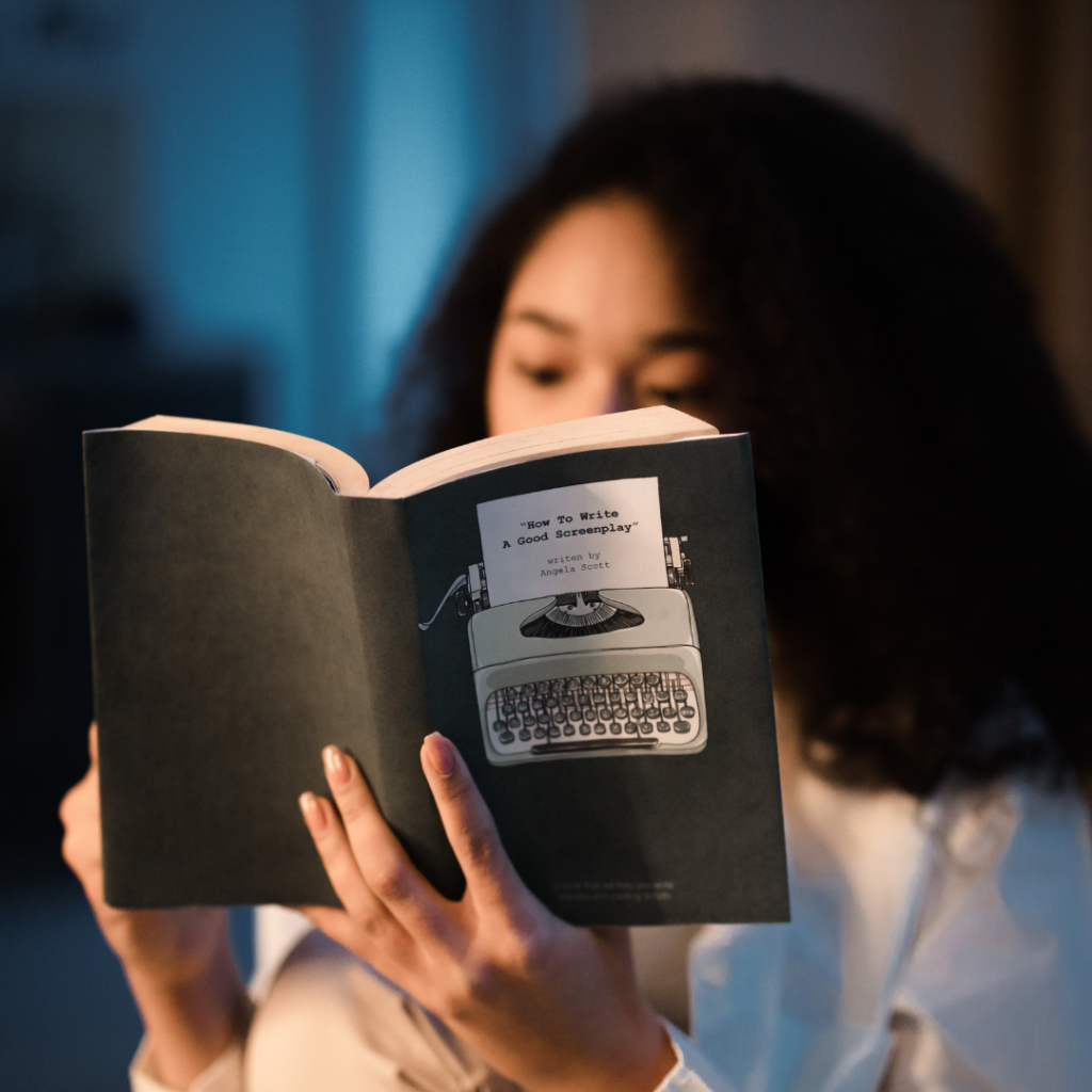 Girl with dark long hair reading paperback black book in dim light