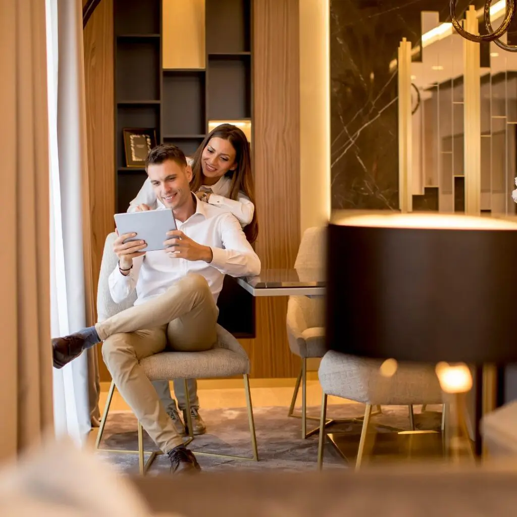Centre for Sight young rich couple sitting in living room hugging each other looking at mobile phone stock image upper class