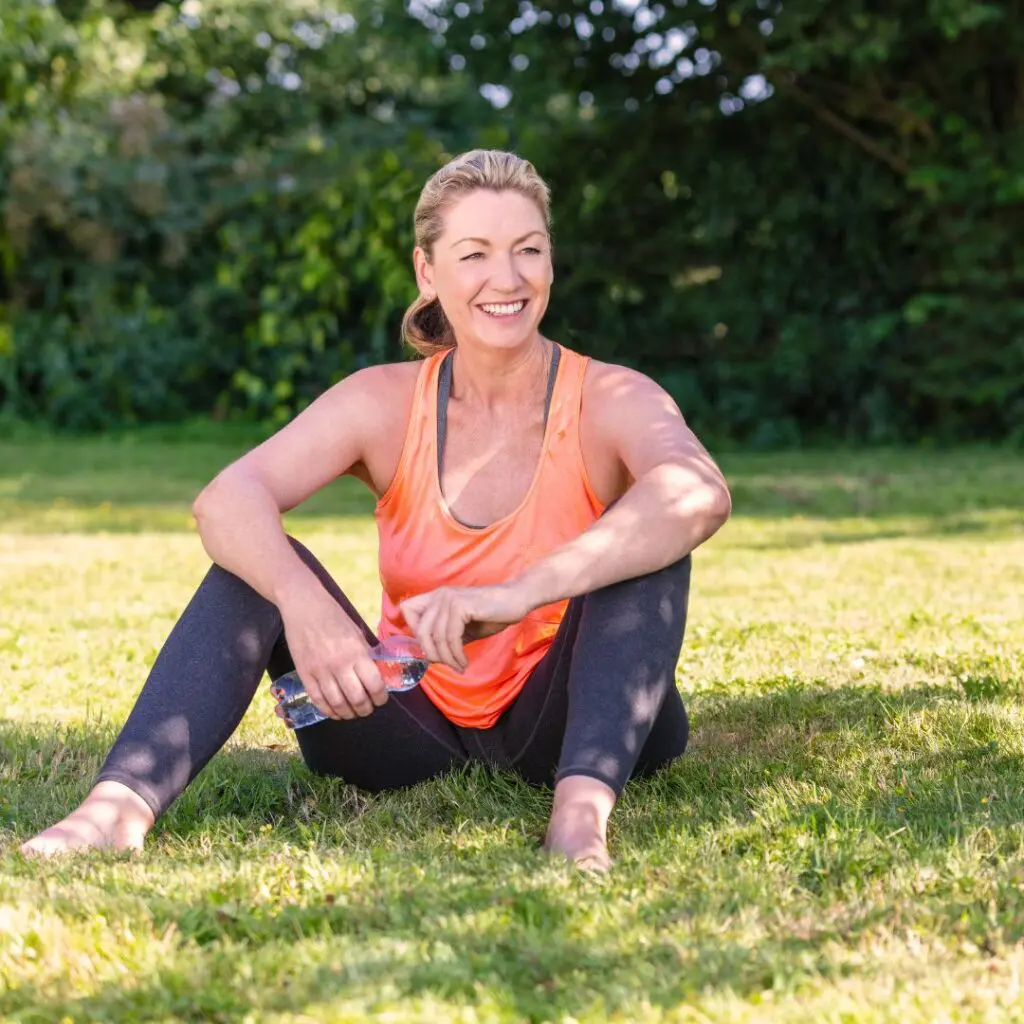 Centre for Sight lady in yoga clothing middle aged gym wear sitting on grass outside holding water bottle stock image for patient event