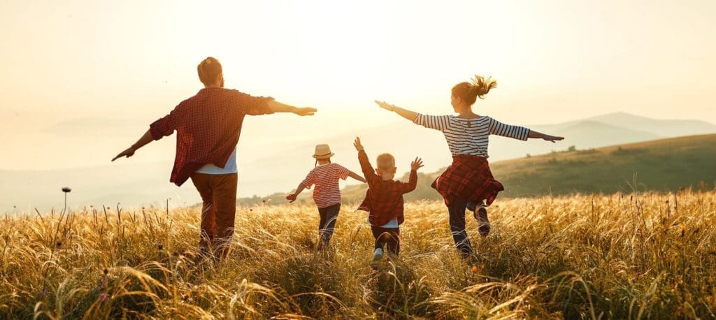 Young family running through a wheat field
