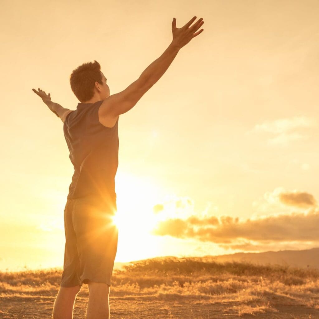 Centre for Sight Man feeling rejuvenated after laser eye surgery looking at sunset with arms out experiencing freedom shorts and tanktop