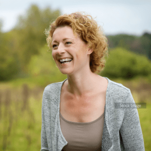Lady smiling outside with grey cardigan curly short blonde hair