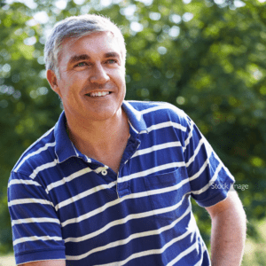 Middle aged man with grey hair with striped shirt sat down smiling outside