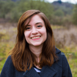 Young girl with short brunette hair smiling in the outside natural reserve trees and long grass