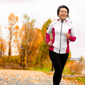 Woman running in park hair tied back autumnal leaves and trees