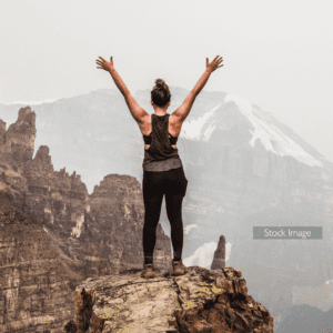 Girl on top of mountain with arms in the air experiencing freedom