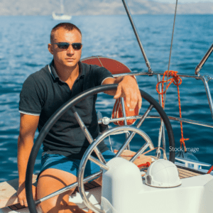 Man on boat in the ocean wearing sunglasses driving the boat