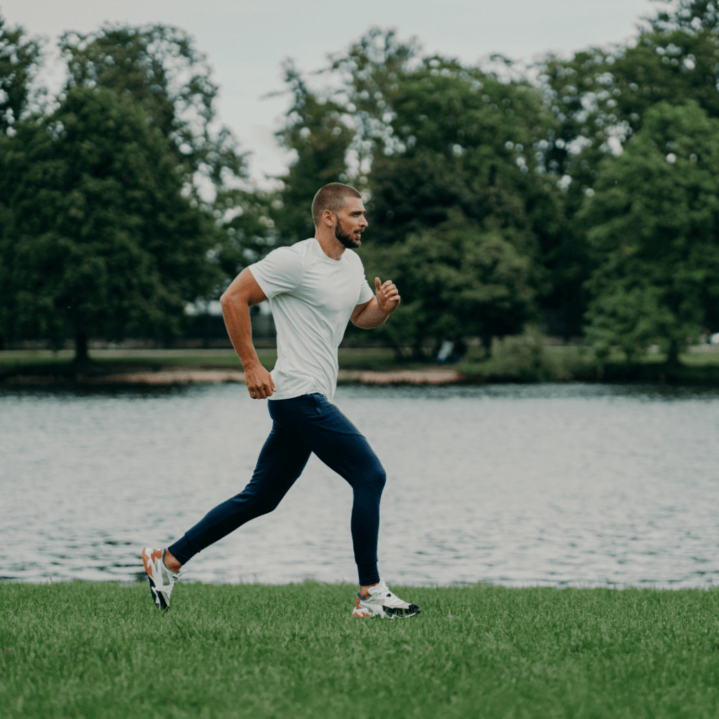 Young Man running on grass along riverbank