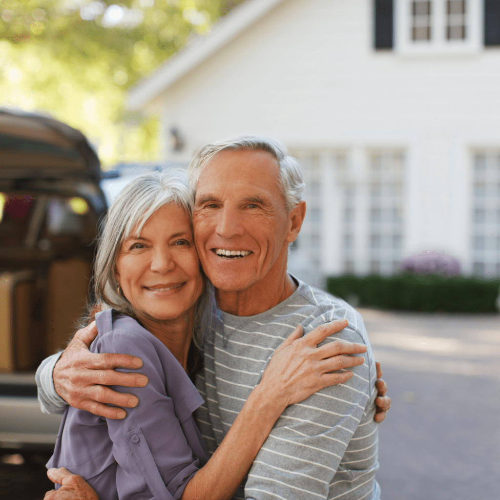 Happy smiling couple smiling outside their home holding each other
