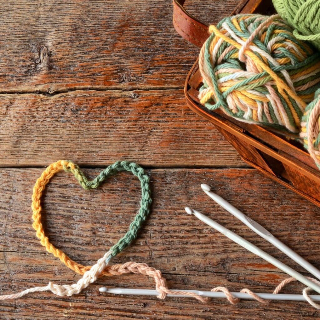 Centre for Sight knitting wool in heart shape and balls of wool for crafting needles and wool in yellow pink green multicolours on wooden table