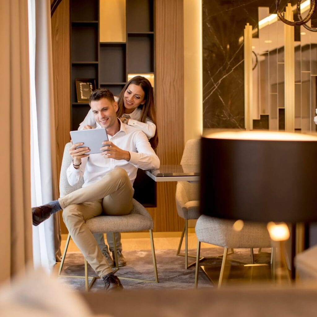 Centre for Sight young rich couple sitting in living room hugging each other looking at mobile phone stock image upper class