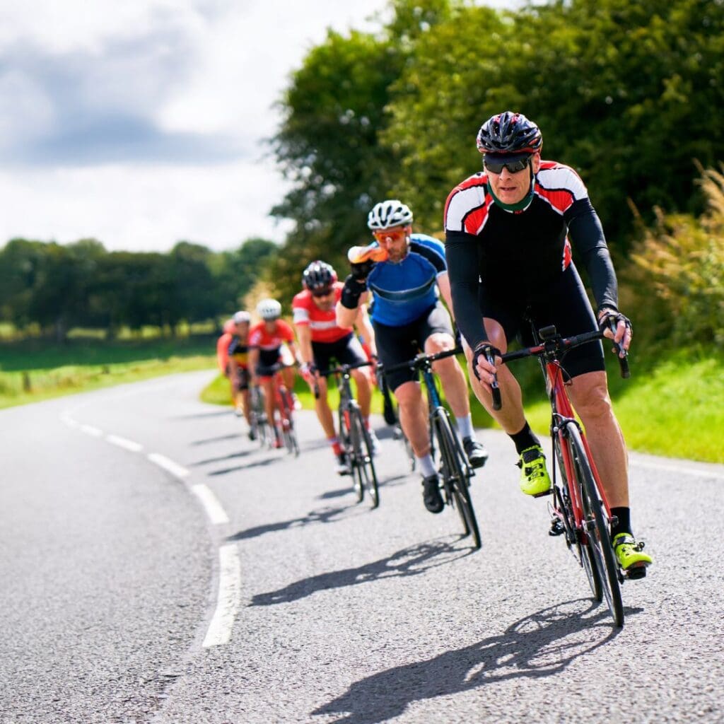 Centre for Sight stock image of cyclists on road bikes in tandem sunny day trees and road