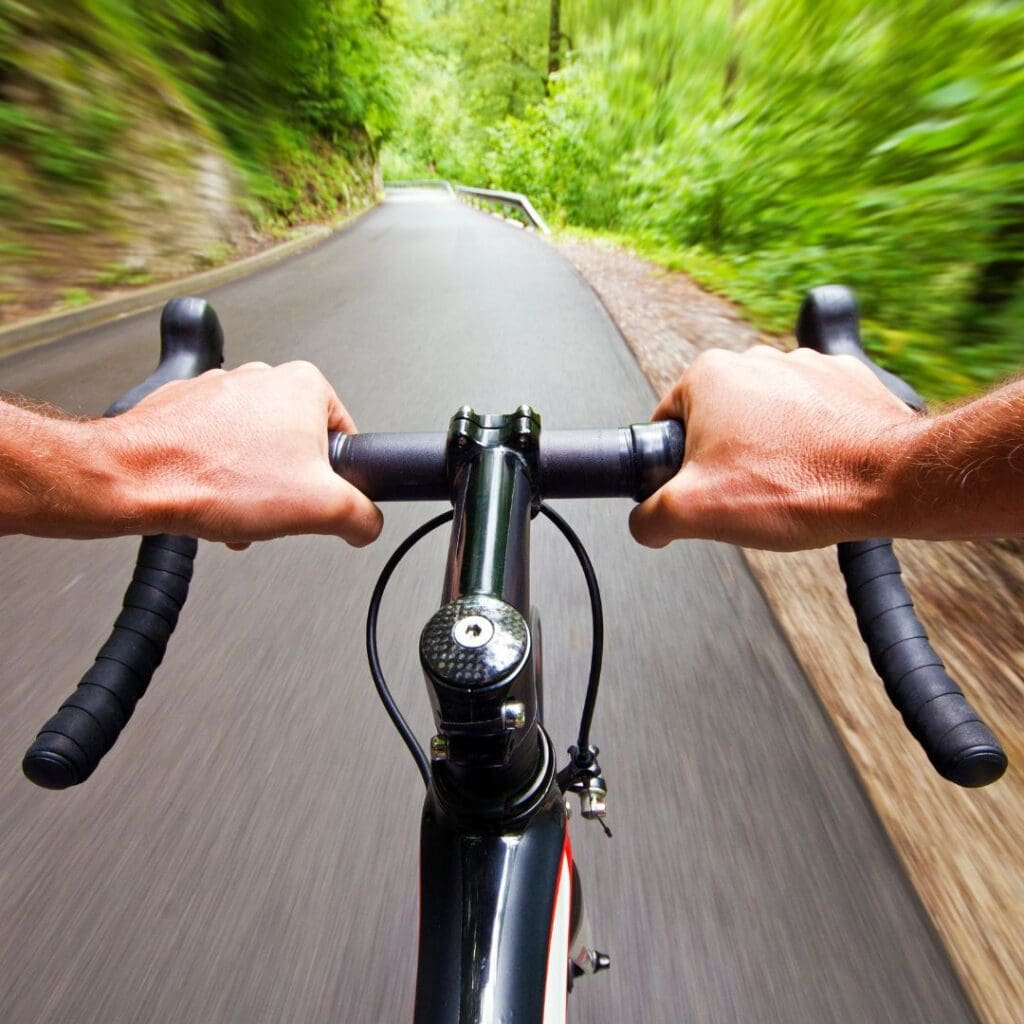 Centre for Sight stock image for vision correction man's hands on the handlebars of a bike riding through wooded area on road