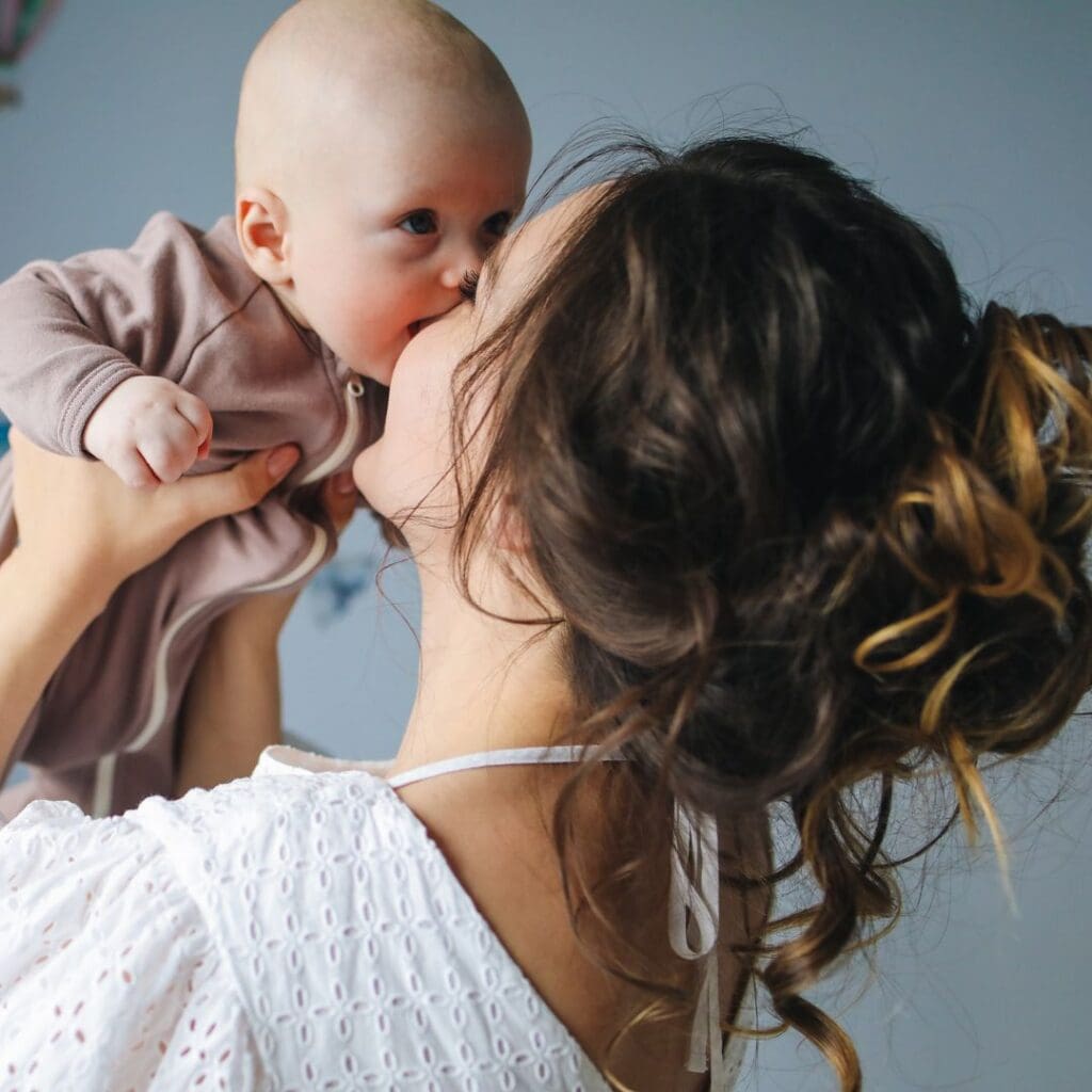 Centre for Sight mother and baby brunette mother with hair in bun holding up baby kissing stock image for blog post Who is NOT suitable for laser eye surgery by Sheraz Daya