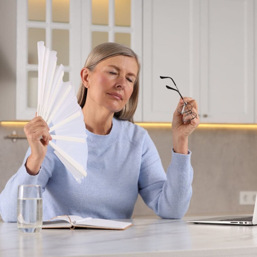 Centre for Sight lady fanning and holding eye glasses with dry eyes because of menopause eye dryness showing link between menopause and dry eyes