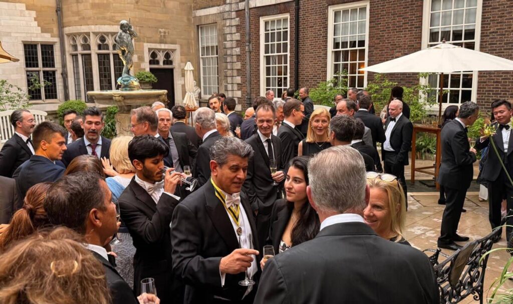 Centre for Sight Marks 30 Years with Ophthalmology Conference on the Future of Vision Care 3 A large group of people dressed in formal attire socialize at an outdoor courtyard reception, celebrating a World First achievement. Some hold drinks and chat, while greenery, tables, and a statue decorate the elegant setting.